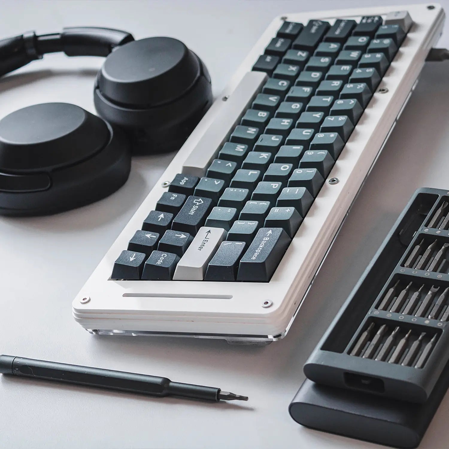 White PigModding Acrylic Custom Mechanical Keyboard on a minimal gaming setup with keyboard tools and headphones.